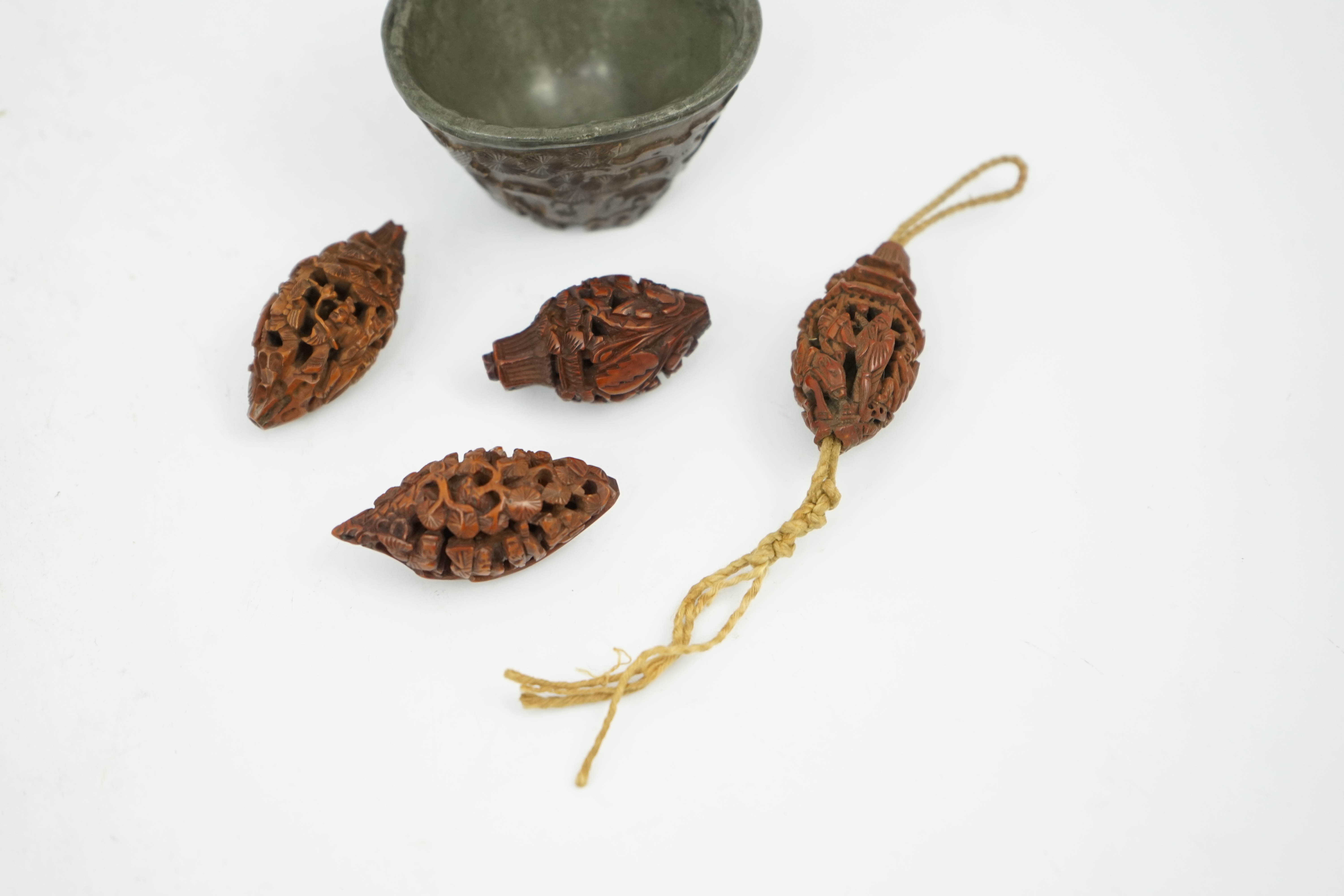 Four Chinese carved peach stones and an 18th/19th century Chinese carved wood cup, 6cm wide (5). Condition - fair to good